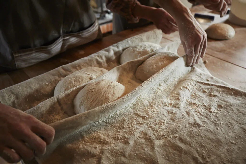 On retrouve des mains de boulanger qui travaille, il y a des boules de pains 